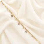 Elegant gold-plated charm bracelet with delicate round charms and cubic stones on wrist