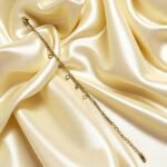 Elegant gold-plated charm bracelet with delicate heart and crystal charms displayed on white silk with roses Elegant Gold-Plated Charm Bracelet for Women