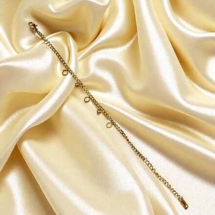 Elegant gold-plated charm bracelet with delicate heart and crystal charms displayed on white silk with roses Elegant Gold-Plated Charm Bracelet for Women