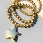 Gold beaded Starer Bracelet Stack with shiny star pendant for women.